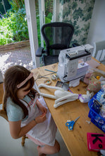 Load image into Gallery viewer, Child sewing a plush toy at a table with sewing machine and materials.