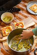 Load image into Gallery viewer, Children participating in a sewing workshop, with materials and partially completed sewing projects visible.