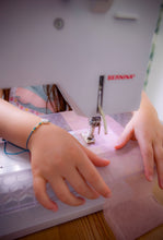 Load image into Gallery viewer, child using a sewing machine with hands guiding fabric., during a moozlehome sewing workshop
