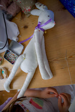 Load image into Gallery viewer, White bunny toy with purple ribbon on a wooden table.
